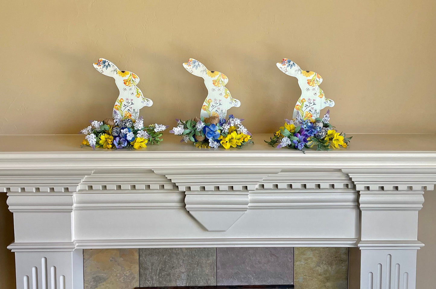 Set of 3 Wooden Standing Painted Easter Bunnies embellished with Blue, Yellow, and Lavender Flowers and Greenery for Easy Holiday Decor.