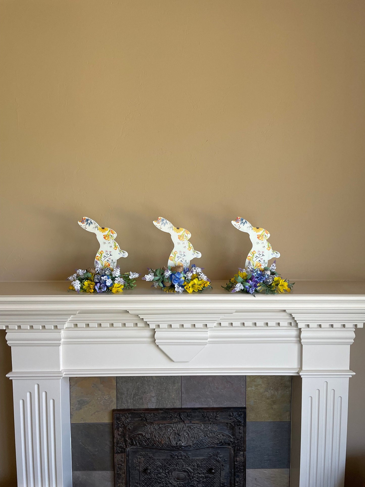 Set of 3 Wooden Standing Painted Easter Bunnies embellished with Blue, Yellow, and Lavender Flowers and Greenery for Easy Holiday Decor.