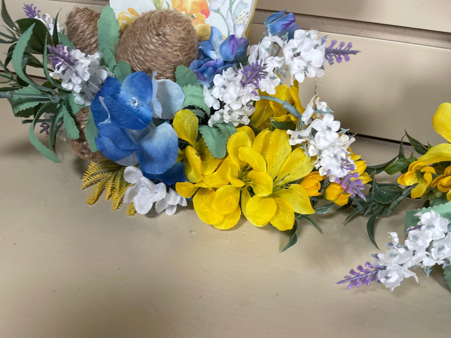 Set of 3 Wooden Standing Painted Easter Bunnies embellished with Blue, Yellow, and Lavender Flowers and Greenery for Easy Holiday Decor.