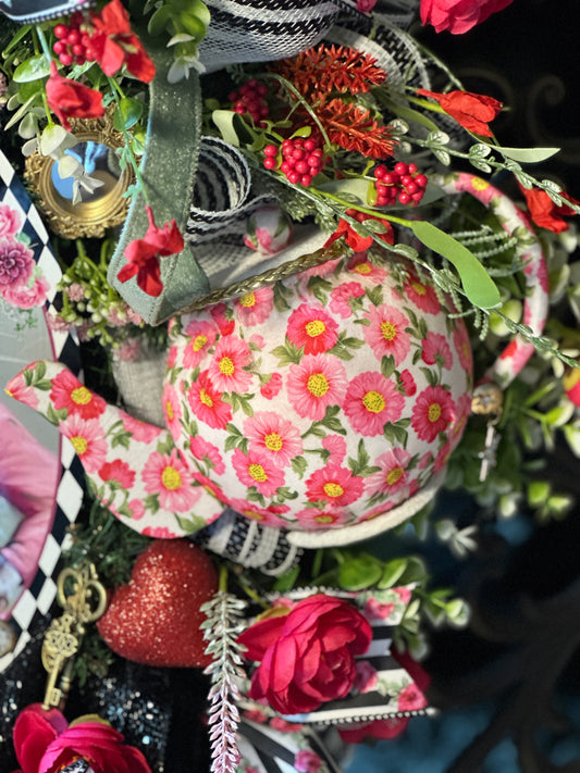 Decorative teapot with floral pattern surrounded by flowers and greenery