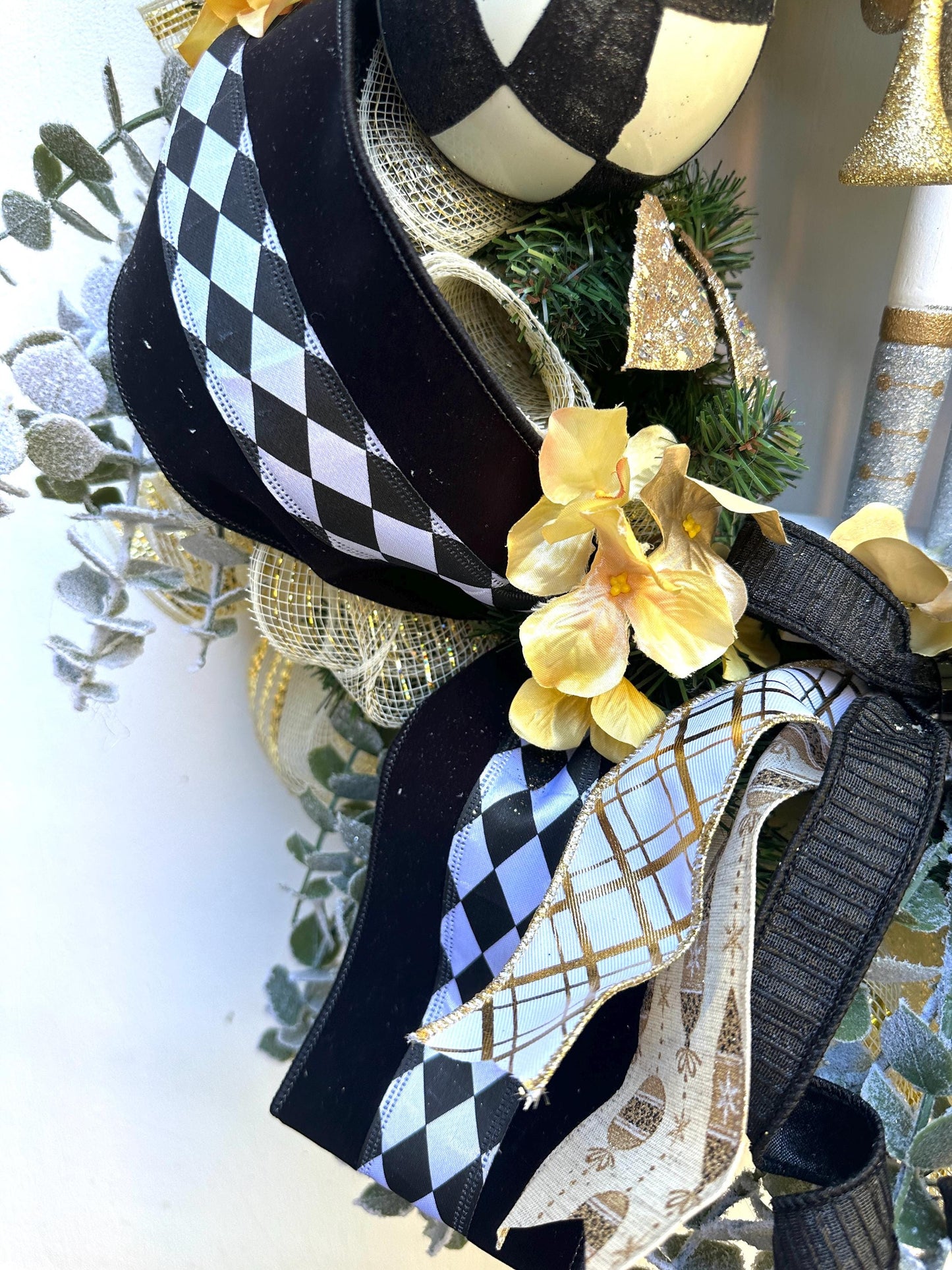 Nutcracker holiday front door Christmas wreath in gold and silver with designer ribbons featuring a wooden figure and black harlequin ribbon