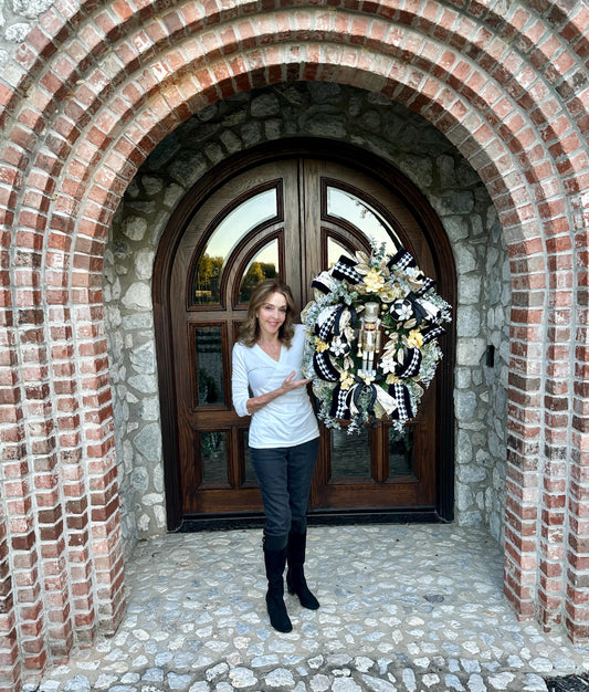 Nutcracker holiday front door Christmas wreath in gold and silver with designer ribbons featuring a wooden figure and black harlequin ribbon