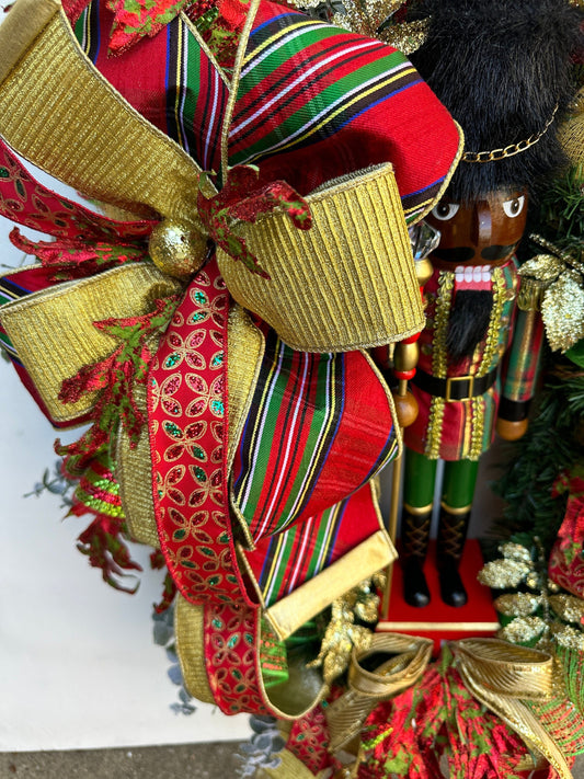 Christmas nutcracker red, green and gold nutcracker wreath features a dark face nutcracker soldier and a designer bow of 3 colorful ribbons.