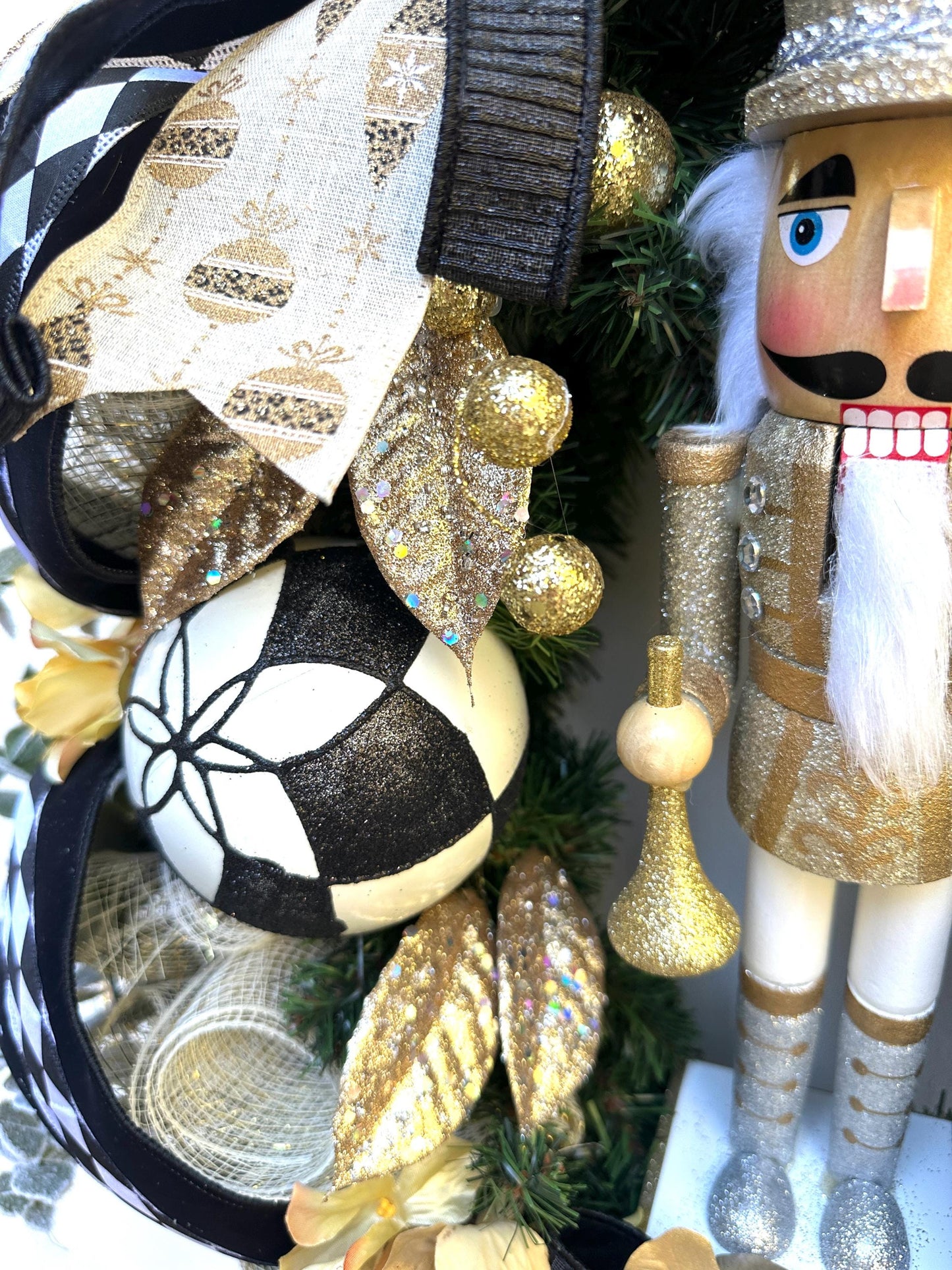 Nutcracker holiday front door Christmas wreath in gold and silver with designer ribbons featuring a wooden figure and black harlequin ribbon