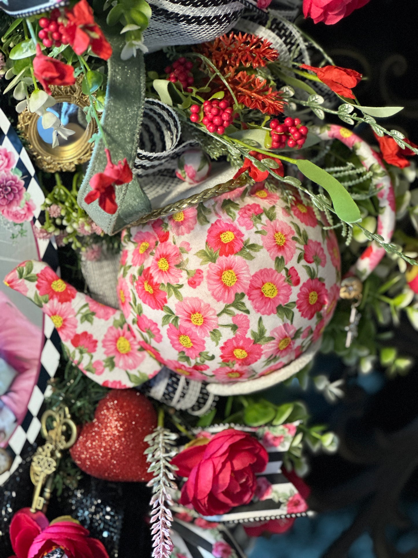 Decorative teapot with floral pattern surrounded by flowers and greenery
