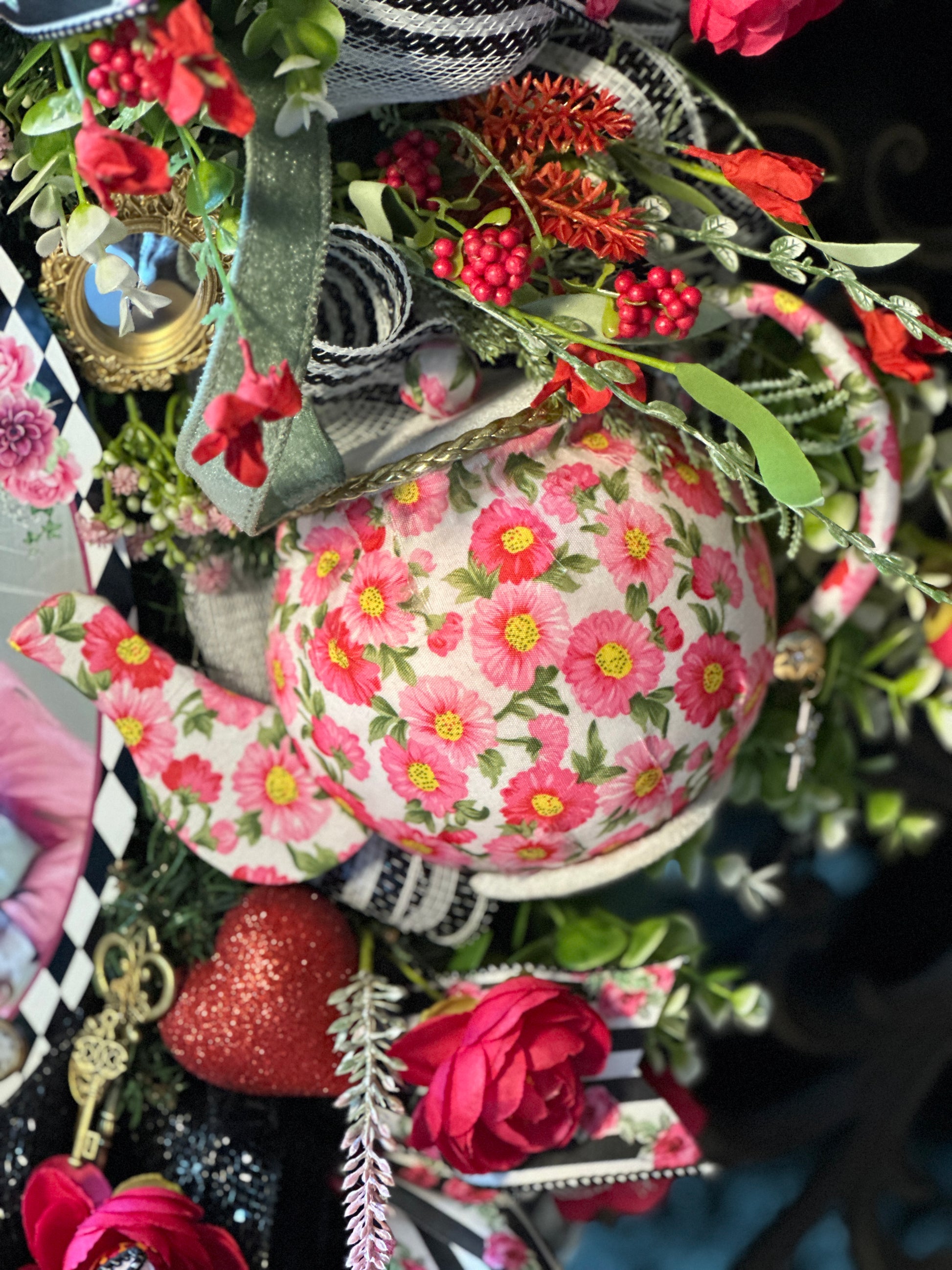 Decorative teapot with floral pattern surrounded by flowers and greenery
