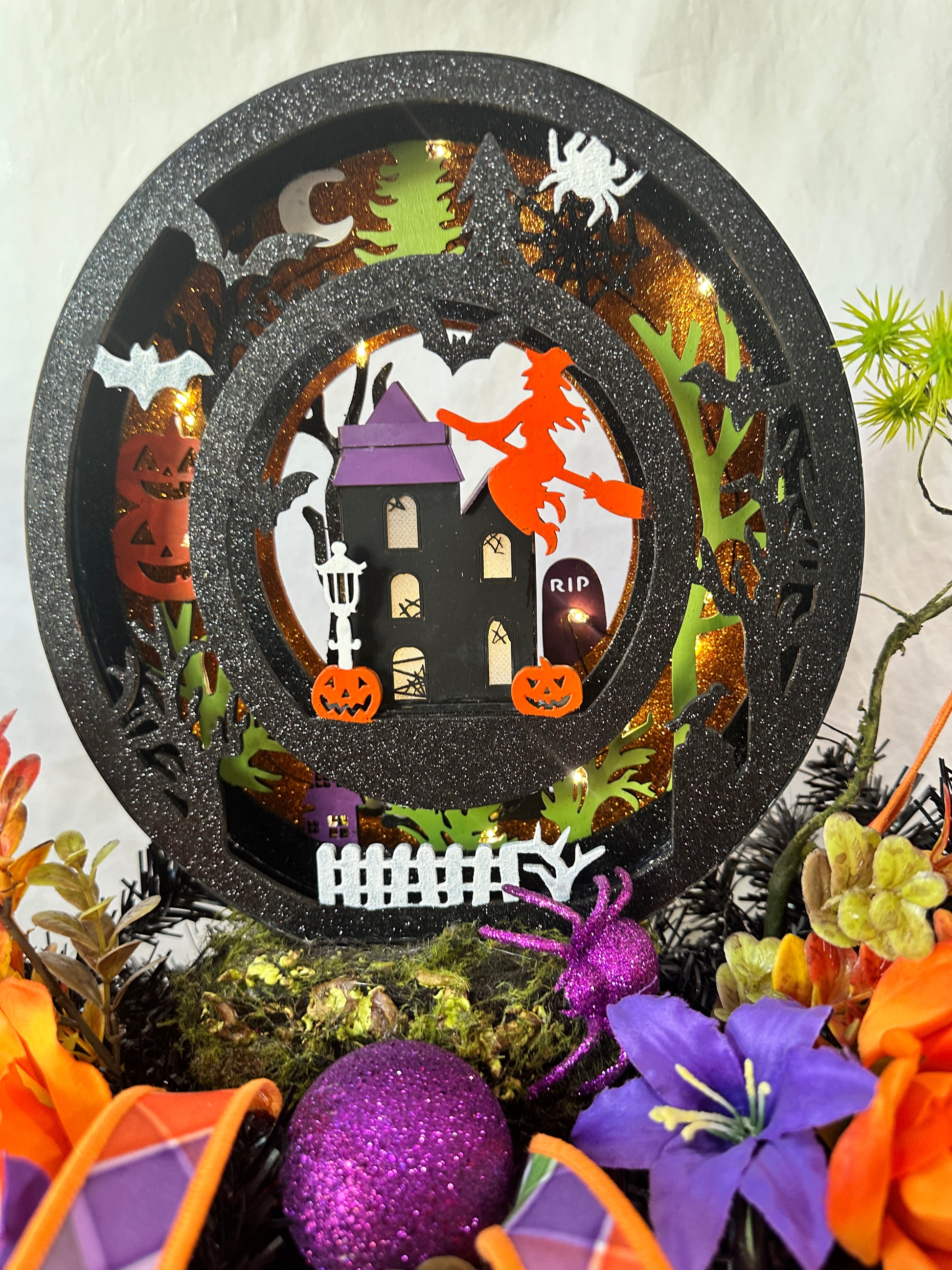 Decorative Halloween plate with haunted house design surrounded by festive decorations.