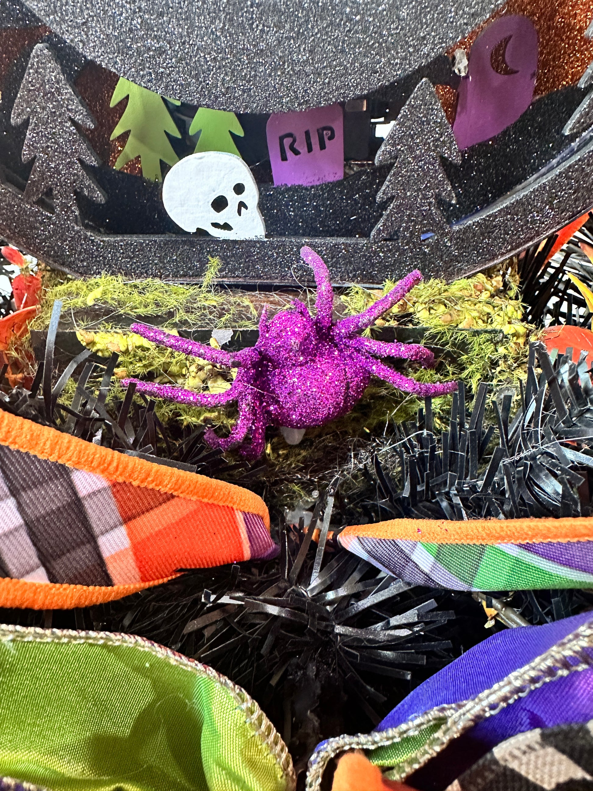 Halloween-themed decorative ribbon with spider, skull, and ribbons in various colors.